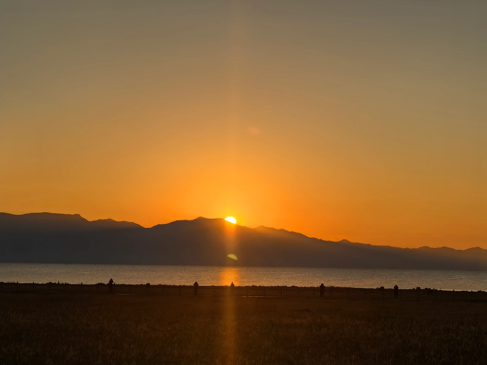 夕阳从远山边缘照向湖面